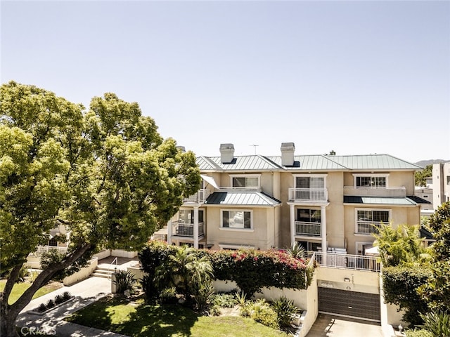 530 W Stocker St Unit 205, Glendale, CA 91202 - view of front facade with a standing seam roof, a chimney, a metal roof, stucco siding, and a garage