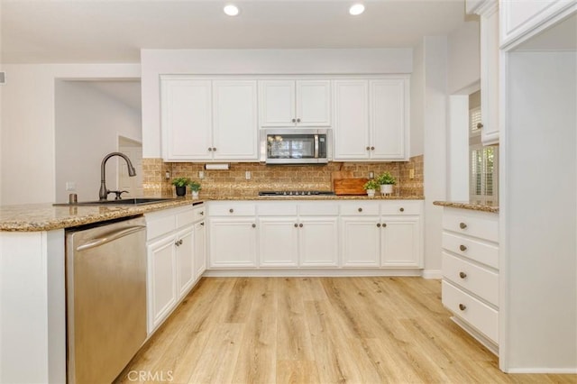 23609 Wilmington Ct, Valencia, CA 91354 - kitchen featuring appliances with stainless steel finishes, light stone countertops, light wood-style flooring, backsplash, and recessed lighting