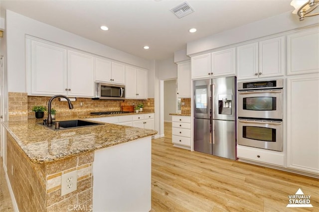 23609 Wilmington Ct, Valencia, CA 91354 - kitchen featuring appliances with stainless steel finishes, white cabinets, light stone counters, a peninsula, and recessed lighting