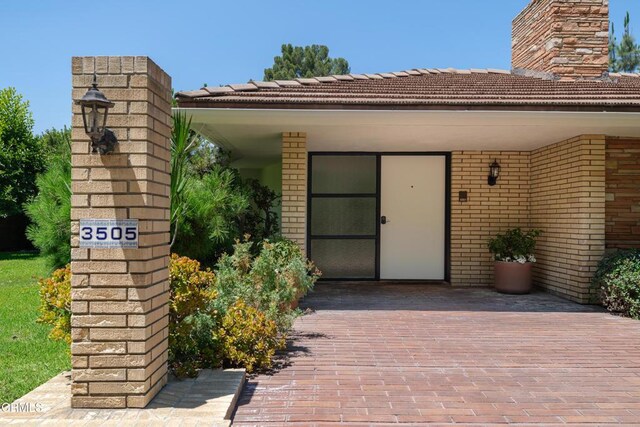 3505 E California Blvd, Pasadena, CA 91107 - view of exterior entry featuring a chimney, brick siding, and a tile roof