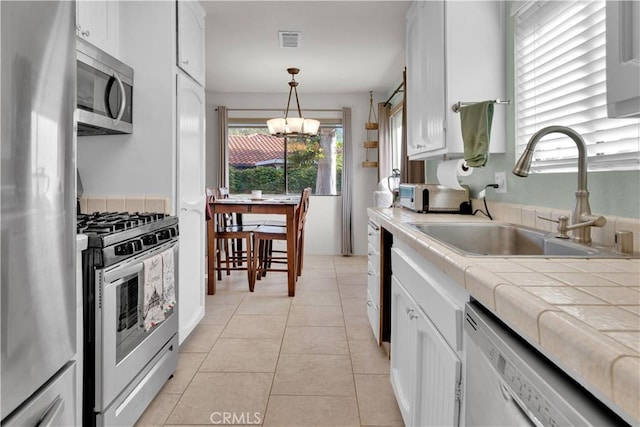 139 Flag Way Unit C, Paso Robles, CA 93446 - kitchen featuring stainless steel appliances, tile counters, a chandelier, white cabinets, and decorative light fixtures