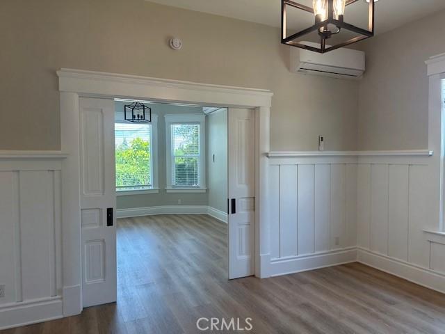 1902 E Citrus Ave, Redlands, CA 92374 - unfurnished dining area with a wall mounted air conditioner, a chandelier, wood finished floors, wainscoting, and a decorative wall