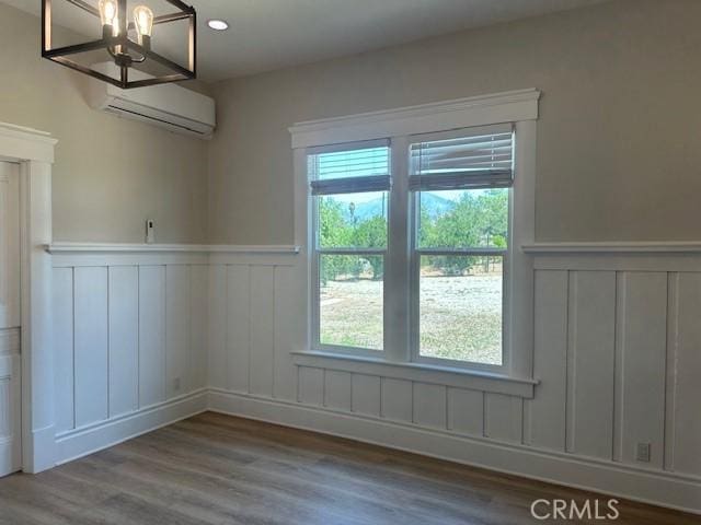1902 E Citrus Ave, Redlands, CA 92374 - empty room featuring a wall unit AC, wainscoting, a decorative wall, plenty of natural light, and a chandelier