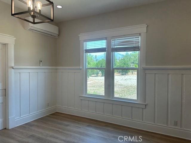 1902 E Citrus Ave, Redlands, CA 92374 - unfurnished dining area featuring a wall mounted air conditioner, wainscoting, a decorative wall, plenty of natural light, and wood finished floors