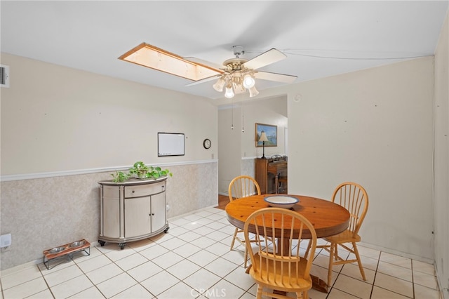 932 Redwood Ct, Corona, CA 92879 - dining area with ceiling fan, a skylight, a wainscoted wall, and light tile patterned flooring