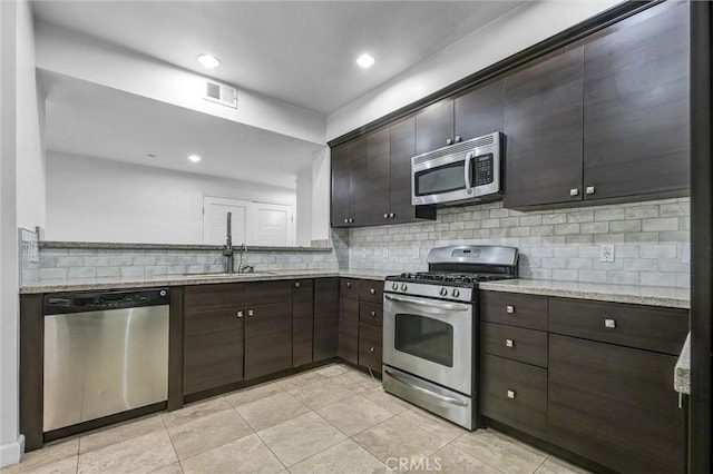 991 Arapahoe St Unit 202A, Los Angeles, CA 90006 - kitchen with appliances with stainless steel finishes, decorative backsplash, dark brown cabinetry, light tile patterned flooring, and light stone countertops