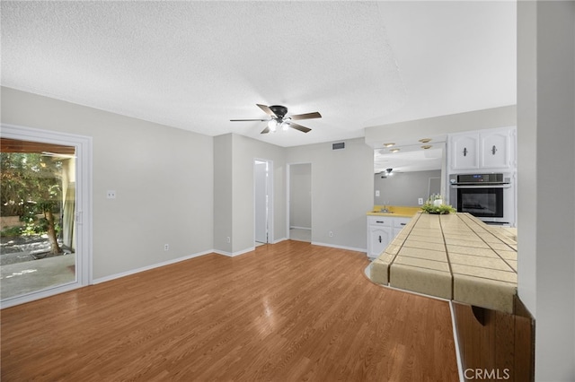 10802 Jordan Rd, Whittier, CA 90603 - unfurnished living room with a ceiling fan, light wood-style floors, and a textured ceiling