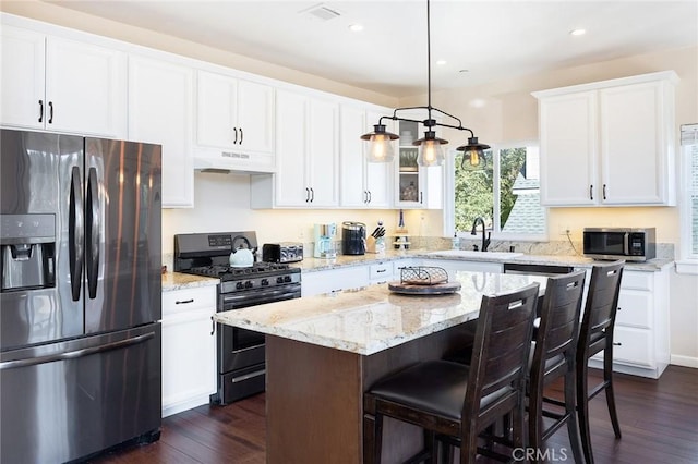 26845 Modoc Ln, Lake Arrowhead, CA 92352 - kitchen featuring stainless steel appliances, under cabinet range hood, dark wood-style floors, a kitchen island, and white cabinets