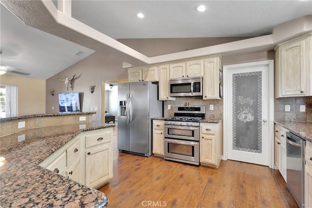 9525 Cambria Ct, Phelan, CA 92371 - kitchen featuring appliances with stainless steel finishes, backsplash, lofted ceiling, dark stone countertops, and wood finished floors