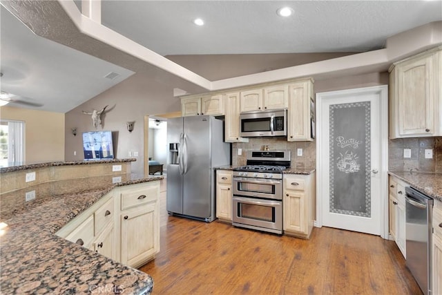 9525 Cambria Ct, Phelan, CA 92371 - kitchen featuring appliances with stainless steel finishes, lofted ceiling, backsplash, dark stone countertops, and wood finished floors