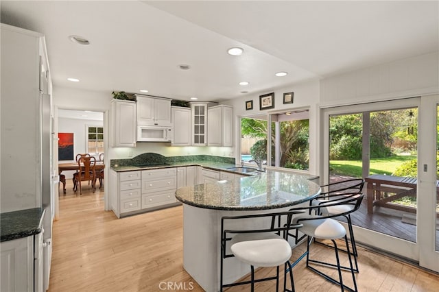 5230 Harbour Heights Ct, San Diego, CA 92109 - kitchen with white microwave, a kitchen breakfast bar, white cabinets, light wood finished floors, and recessed lighting