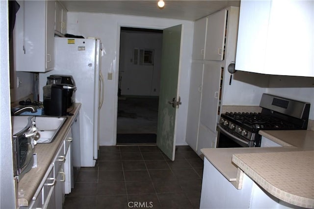 12570 Jacaranda Pl, Chino, CA 91710 - kitchen with stainless steel gas range oven, dark tile patterned floors, white cabinets, and light countertops