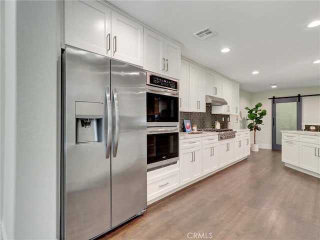 23034 Park Este, Calabasas, CA 91302 - kitchen with stainless steel appliances, recessed lighting, under cabinet range hood, a barn door, and tasteful backsplash