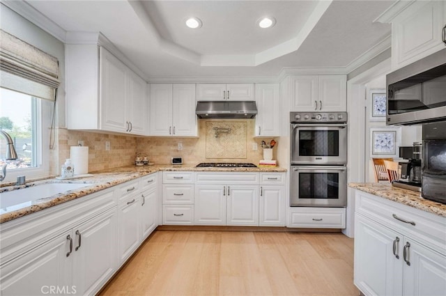 6140 Meadow Lark Dr, La Verne, CA 91750 - kitchen with stainless steel appliances, under cabinet range hood, white cabinetry, a tray ceiling, and light wood-style flooring