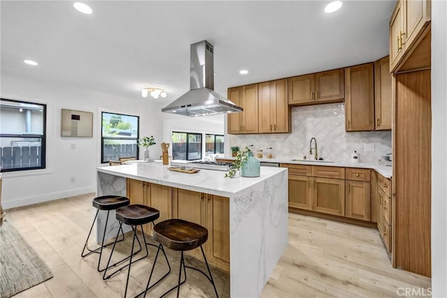 57 S Grand Oaks Ave, Pasadena, CA 91107 - kitchen featuring island exhaust hood, a kitchen island, backsplash, a breakfast bar area, and brown cabinetry