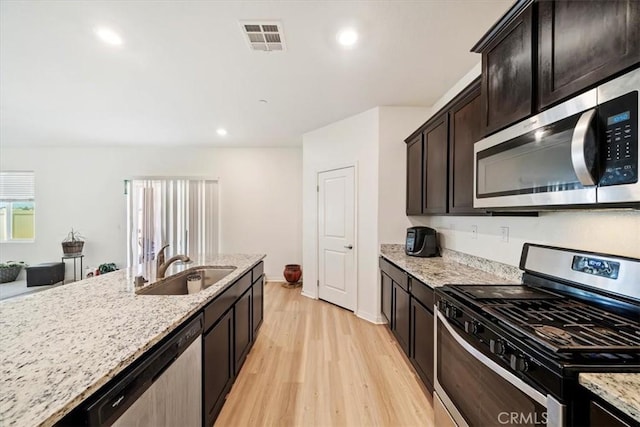 16814 Desert Star St, Victorville, CA 92394 - kitchen with appliances with stainless steel finishes, light wood finished floors, light stone counters, recessed lighting, and dark brown cabinetry