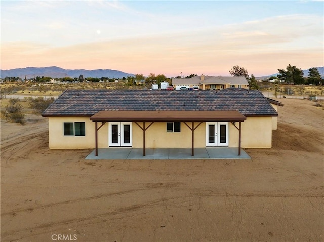 11228 Mockingbird, Apple Valley, CA 92308 - back of house at dusk with french doors, stucco siding, a patio area, and a mountain view