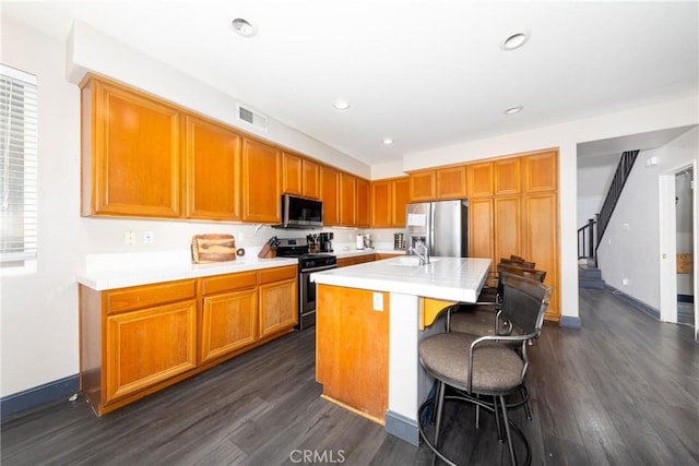 26 Billings Ave, Beaumont, CA 92223 - kitchen with appliances with stainless steel finishes, dark wood-type flooring, light countertops, a center island with sink, and a breakfast bar