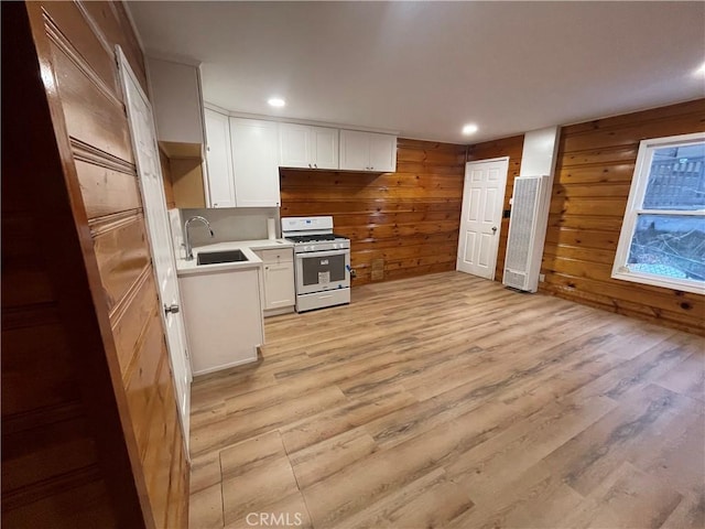 651 Community Dr, Lake Arrowhead, CA 92352 - kitchen with white gas stove, a heating unit, light wood-style flooring, white cabinets, and wood walls
