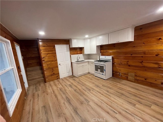 651 Community Dr, Lake Arrowhead, CA 92352 - kitchen with gas range gas stove, wood walls, white cabinetry, light wood-style flooring, and recessed lighting