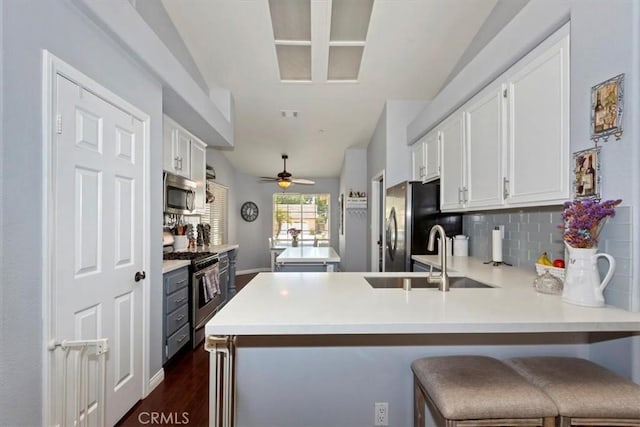 6939 Fremontia Ave, Fontana, CA 92336 - kitchen featuring stainless steel appliances, white cabinets, a peninsula, backsplash, and light countertops