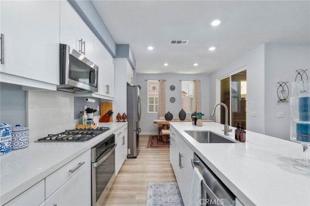 8234 Traveller St, Chino, CA 91710 - kitchen with stainless steel appliances, white cabinetry, light countertops, recessed lighting, and light wood-type flooring