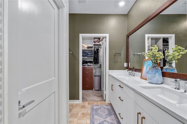 8234 Traveller St, Chino, CA 91710 - bathroom with double vanity, a spacious closet, stone finish floors, and a textured wall