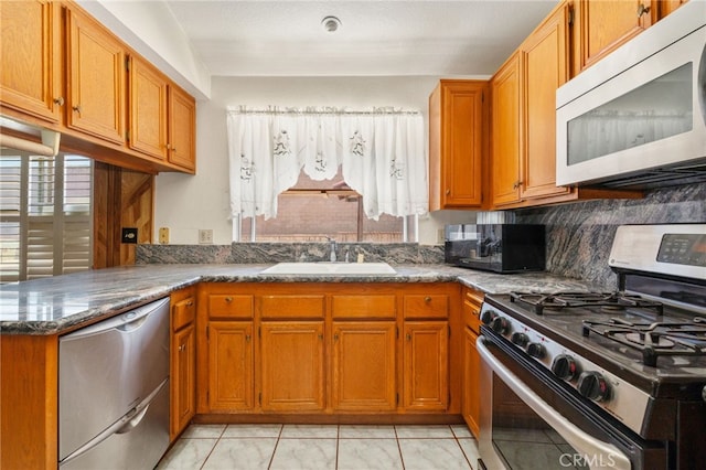 22533 Kinross Ln, Moreno Valley, CA 92557 - kitchen featuring stainless steel appliances, light tile patterned floors, brown cabinetry, and dark stone counters