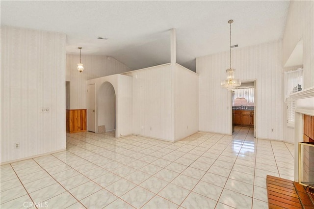 22533 Kinross Ln, Moreno Valley, CA 92557 - empty room with wallpapered walls, vaulted ceiling, arched walkways, a chandelier, and light tile patterned floors