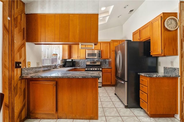 22533 Kinross Ln, Moreno Valley, CA 92557 - kitchen with stainless steel appliances, a peninsula, brown cabinets, light tile patterned floors, and dark stone counters