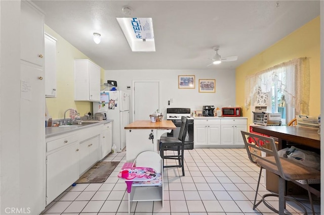 6186 Abronia Ave Unit 29, Palms, CA 92277 - kitchen with electric stove, freestanding refrigerator, white cabinets, ceiling fan, and wooden counters