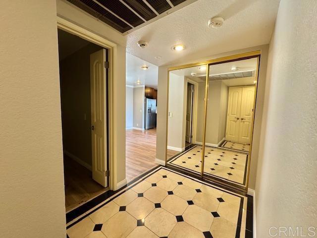 4545 Arizona St Unit 104, San Diego, CA 92116 - corridor with inlaid floor details, a textured wall, and tile patterned flooring