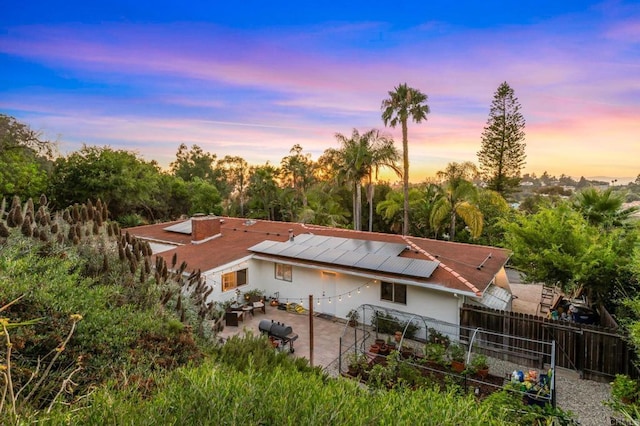 1670 Alta Vista Dr, Vista, CA 92084 - back of property at dusk featuring a patio area, roof mounted solar panels, and stucco siding