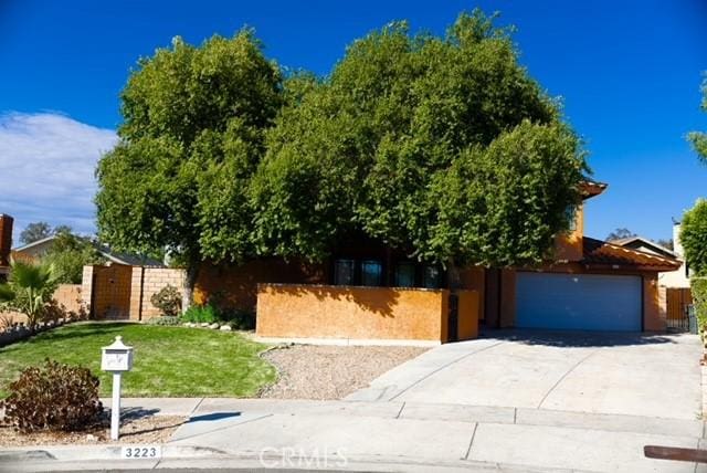 3223 Algonquin Ln, Riverside, CA 92503 - view of property hidden behind natural elements featuring concrete driveway and an attached garage