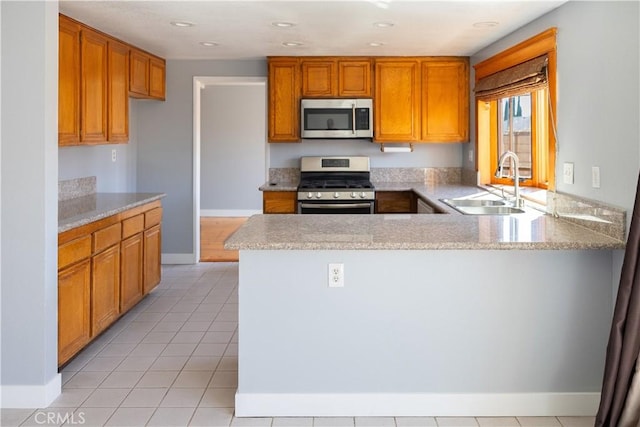 3223 Algonquin Ln, Riverside, CA 92503 - kitchen with appliances with stainless steel finishes, a peninsula, brown cabinets, and light tile patterned floors