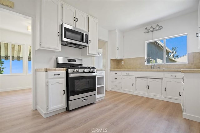 5609 Clark Ave, Lakewood, CA 90712 - kitchen featuring appliances with stainless steel finishes, white cabinets, light wood finished floors, and decorative backsplash