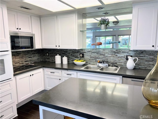 13310 N Fairfield Ln Unit M7 176L, Seal Beach, CA 90740 - kitchen featuring stainless steel microwave, oven, black electric stovetop, dark countertops, and white cabinetry