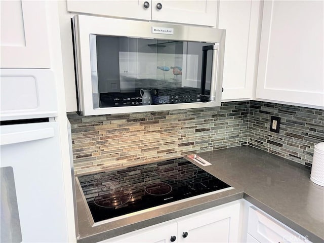 13310 N Fairfield Ln Unit M7 176L, Seal Beach, CA 90740 - kitchen featuring black electric stovetop, tasteful backsplash, white cabinetry, and stainless steel microwave