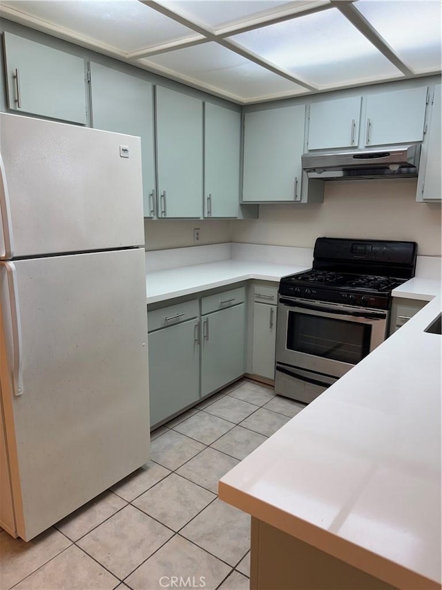 2501 W Redondo Beach Blvd Unit 317, Gardena, CA 90249 - kitchen with freestanding refrigerator, stainless steel gas range oven, under cabinet range hood, light tile patterned floors, and light countertops