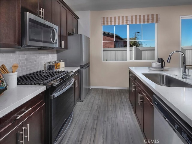 2141 Bergamot St, Redlands, CA 92374 - kitchen with appliances with stainless steel finishes, light wood-style floors, light countertops, decorative backsplash, and dark brown cabinets
