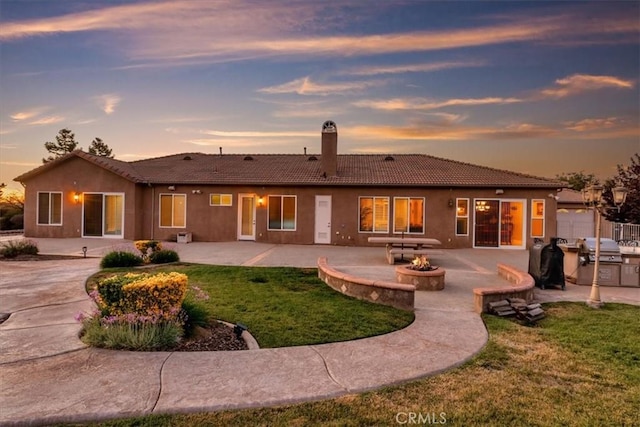22515 Santa Clarita Corte, Perris, CA 92570 - back of house featuring an outdoor fire pit, a tile roof, a chimney, a lawn, and a patio area