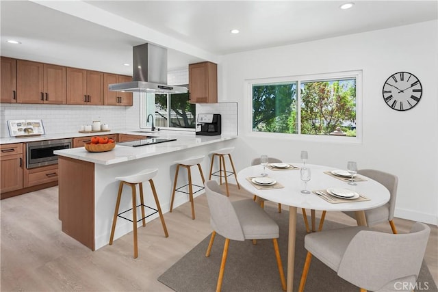 1214 Wilder St, Thousand Oaks, CA 91362 - kitchen featuring island exhaust hood, a peninsula, stainless steel microwave, a breakfast bar area, and decorative backsplash