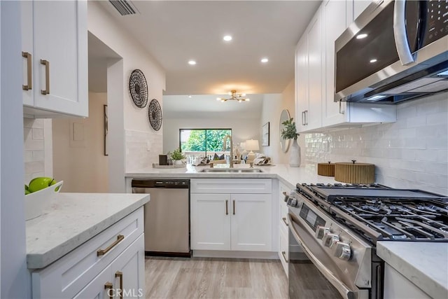 321 Orange Blossom Unit 166, Irvine, CA 92618 - kitchen featuring appliances with stainless steel finishes, backsplash, white cabinets, light stone counters, and recessed lighting