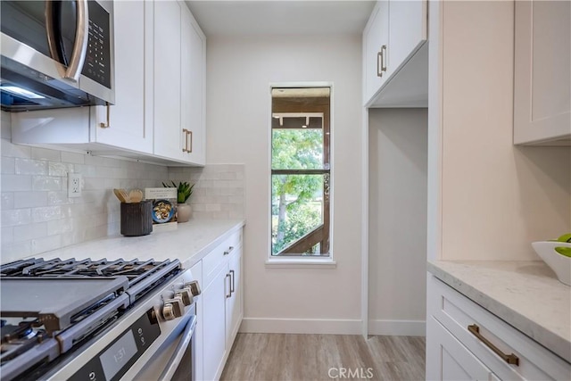 321 Orange Blossom Unit 166, Irvine, CA 92618 - kitchen with stainless steel appliances, decorative backsplash, light wood-style flooring, light stone countertops, and white cabinets