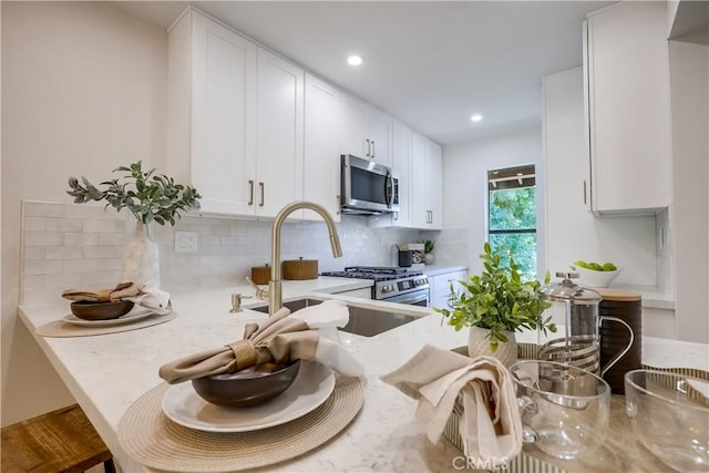 321 Orange Blossom Unit 166, Irvine, CA 92618 - kitchen with appliances with stainless steel finishes, tasteful backsplash, white cabinets, recessed lighting, and light stone countertops