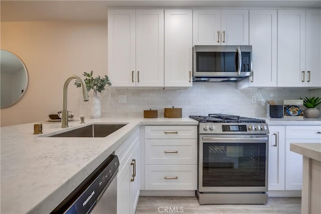 321 Orange Blossom Unit 166, Irvine, CA 92618 - kitchen featuring stainless steel appliances, white cabinetry, decorative backsplash, and light stone counters