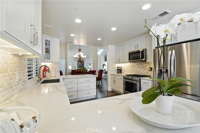 14 Bridgewood Unit 22, Irvine, CA 92604 - kitchen featuring appliances with stainless steel finishes, backsplash, a chandelier, recessed lighting, and light stone countertops