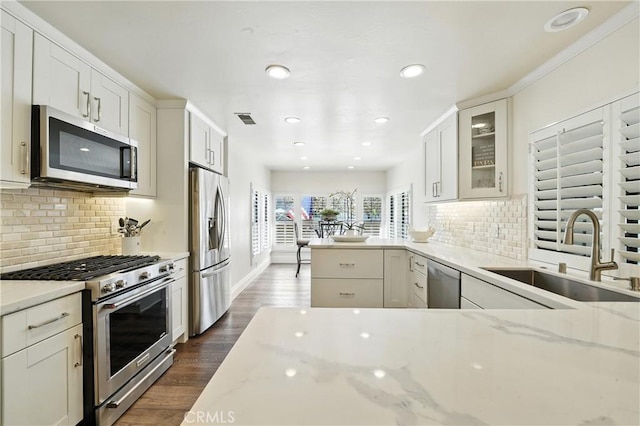 14 Bridgewood Unit 22, Irvine, CA 92604 - kitchen featuring stainless steel appliances, light stone counters, glass insert cabinets, backsplash, and recessed lighting