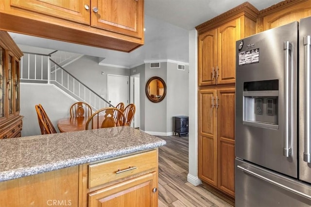 817 Granite Privado, Ontario, CA 91762 - kitchen with stainless steel fridge with ice dispenser, light wood-style floors, brown cabinets, a wood stove, and light stone counters