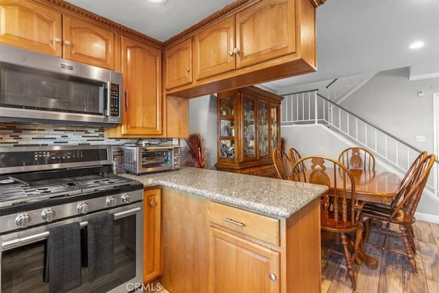 817 Granite Privado, Ontario, CA 91762 - kitchen featuring appliances with stainless steel finishes, light wood-style flooring, a peninsula, brown cabinets, and light stone counters